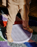 Kind balanciert auf einem Stapelstein® Board light violet auf einem Teppich