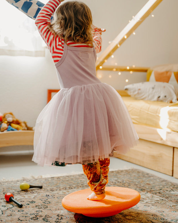 Kind balanciert auf einem orangenen Stapelstein® Board