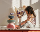Ein Kind sitzt neben einer Skulptur aus Stapelstein® Inside rainbow pastel Elementen