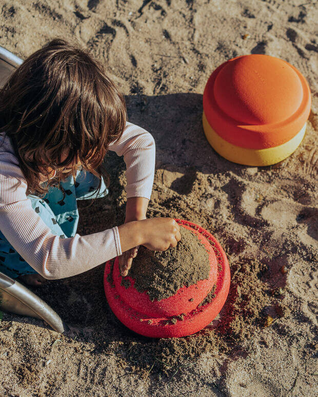 Kind spielt mit Stapelstein Original warm classic im Sand