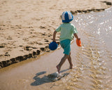 Kind rennt mit Stapelstein® Inside Elementen am Strand durchs Wasser