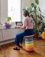 Frau arbeitet am Schreibtisch und sitzt auf dynamischem Hocker aus Stapelstein Original pastel mit Board