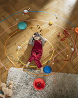 Kind liegt auf dem Boden inmitten von Stapelstein® Inside Elementen und anderen Spielsachen