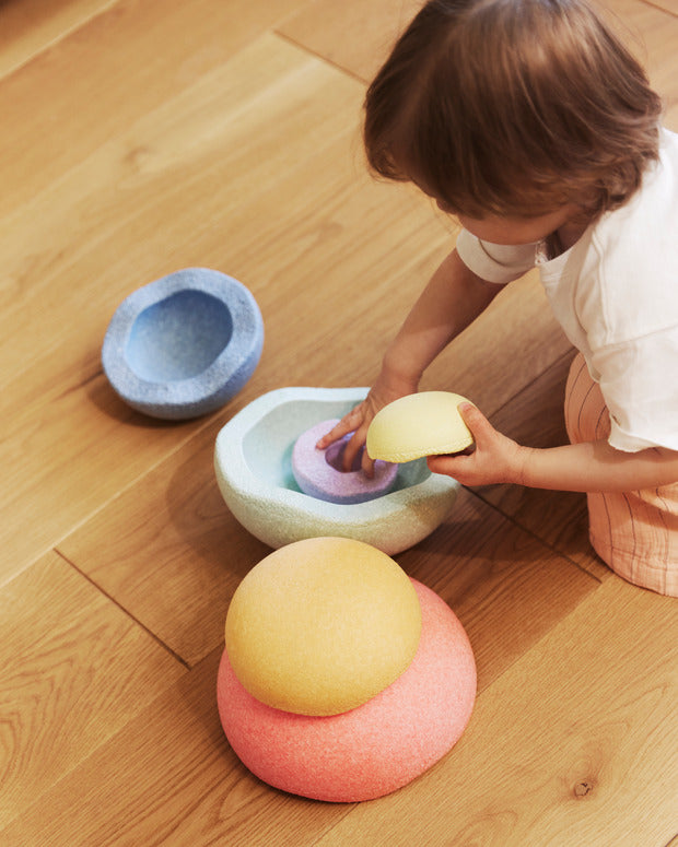 Kind spielt auf dem Boden mit Stapelstein Inside rainbow pastel