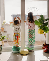 Kinder stehen erhöht auf einem Turm aus Stapelstein® Originals und bemalen ein Fenster