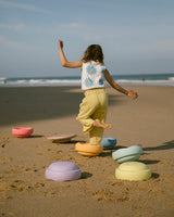 Kind balanciert am Strand über ein Rainbow Set pastel