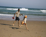 Vater und Kind rennen am Strand und halten Stapelstein® Elemente in den Händen