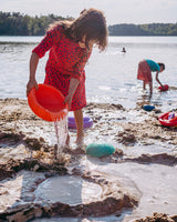 Kind spielt mit Stapelstein® Inside am Strand mit Wasser